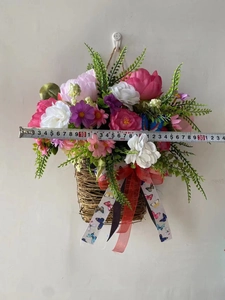 Detail view of artificial flower hanging basket with pink blooms and a red bow accent
