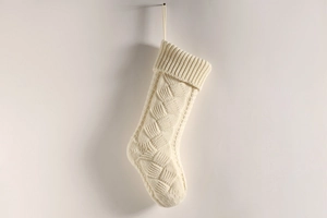 Detailed close-up of a large white cable-knit Christmas stocking with a hanging loop
