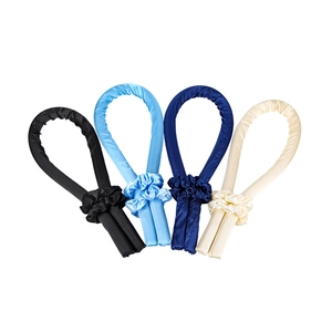 Detail shot of four colorful satin heatless hair curlers in black, blue, and cream