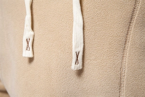 Macro detail of beige fleece hoodie fabric texture with braided drawstring close-up view