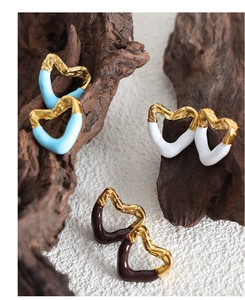 Close-up of heart-shaped earrings in blue, white, and brown enamel with gold textures