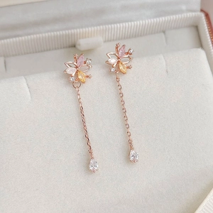 Detail of rose gold dangle earrings featuring multicolor zircons and teardrop pendants