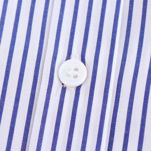 Macro detail of blue and white striped cotton fabric with a white four-hole button