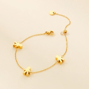 Close-up of golden stainless steel chain bracelet featuring three cartoon figure pendants