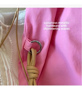 Dettaglio di tessuto in nylon rosa con anello in metallo argentato e cordino kaki