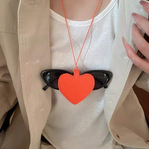 Detail view of heart-shaped orange leather sunglasses holder necklace on a model