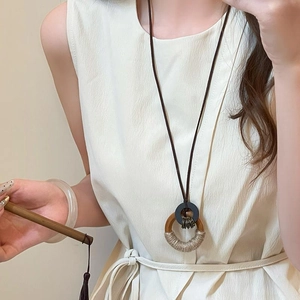 Long leather cord necklace featuring black ring and rope-wrapped wooden circle charm