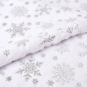 Close-up of white plush Christmas tree skirt with shiny silver snowflake patterns