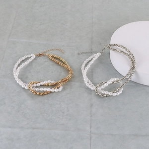 Detailed view of layered necklace with polished metal beads and imitation pearls