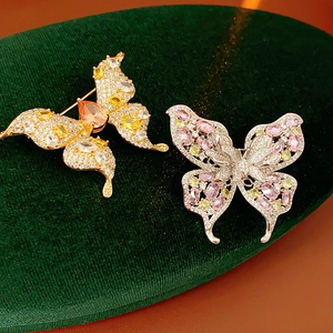 Detailed close-up of butterfly brooches with shimmering zircons in gold and silver finish