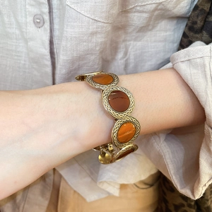Detail showing vintage gold chain bracelet with leopard print stone on linen fabric