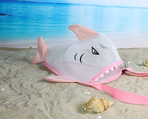 Pink and white mesh shark beach bag for children shown on a sunny beach background