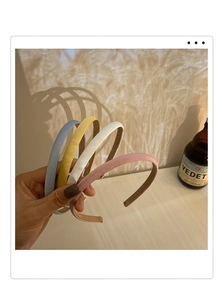 Détail de quatre serre-têtes en satin coloré en bleu, jaune, blanc et rose pastel