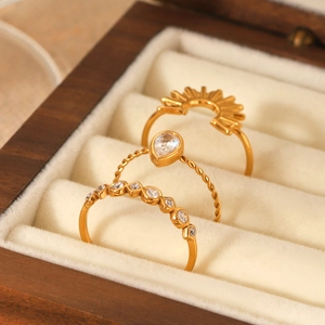 Detailed view of three 18k gold rings with sparkling zircons set in a wooden jewelry box