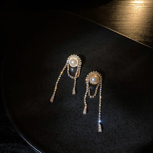 Detailed macro of golden tassel earrings with sparkling rhinestones and white pearls