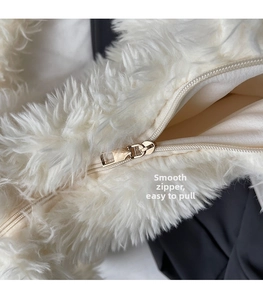 Detail of smooth gold metal zipper and white faux fur texture on the tote bag