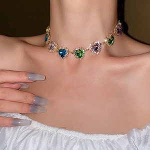 Close-up of golden necklace with colorful heart-shaped gems worn on the neck