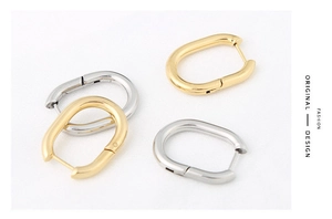 Detailed view of U-shaped oval earrings in gold and silver finish with polished surface