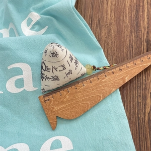Detail shot of zongzi-shaped cloth sachet with jade bead and ruler showing 6cm width