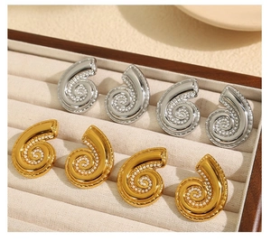 Detailed view of spiral conch earrings in gold and silver finish with pearl accents