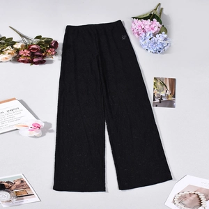 Flat lay of black sheer lace wide leg pants for women with floral decor on a grey background