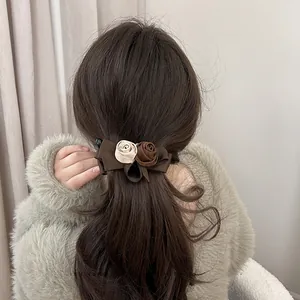 Close-up of vintage fabric rose banana clip with cream and brown flower accents