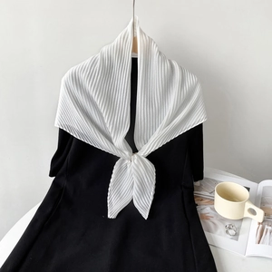 Detail of white pleated square scarf tied on black garment showing light texture
