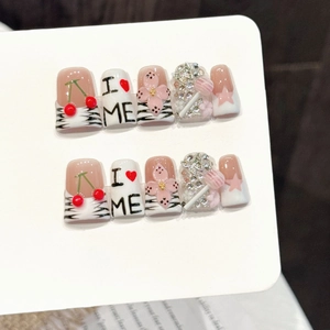 Handmade press-on nails with pink cherry designs, 3D floral accents, and sparkling crystals