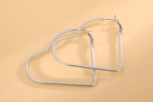 Macro detail of large silver heart hoop earrings with spiral textured stainless steel finish