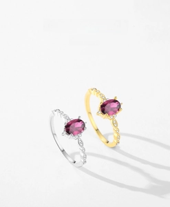 Close-up of vintage engraved silver and gold rings with oval purple gemstones and zircons