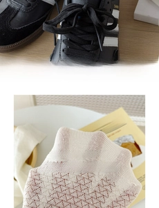 Close-up of beige knit socks with geometric hollow patterns and black leather sneakers