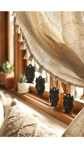 Détail d'un poids de nappe hibou en fonte rétro clipsé sur un tissu en lin beige