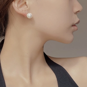 Close-up of elegant round pearl earrings worn by a model in a minimalist style