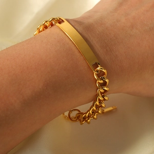 Bracelet gourmette en acier inoxydable doré avec plaque lisse porté sur le poignet
