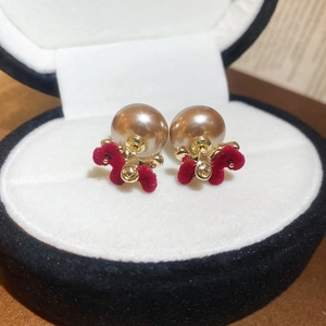Macro shot of vintage champagne pearl earrings with deep red velvet bows in a jewelry box