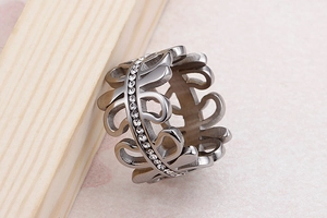 Detailed view of silver hollow leaf ring with sparkling crystals on wood stand