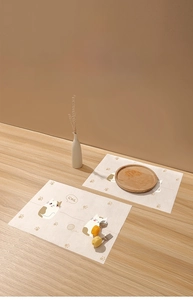 Detail of disposable baby placemat with cute cat patterns on a light wooden table