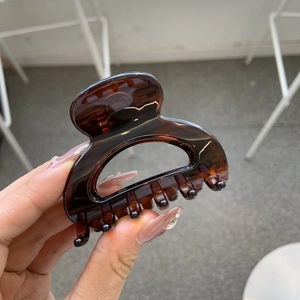 Close-up of tortoise shell pattern hair claw clip with glossy brown amber finish