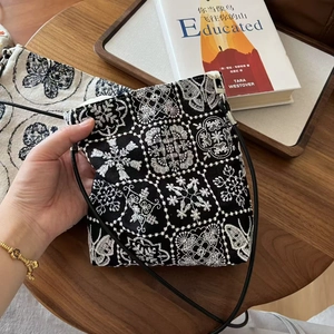 Gros plan détaillé sur la broderie florale blanche d'un sac bandoulière noir en toile de coton