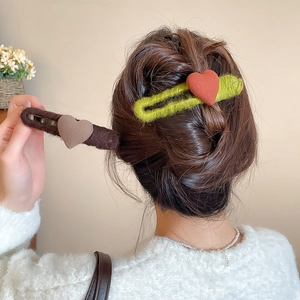 Detailed view of plush heart hair clips in green and brown wool on model's hair