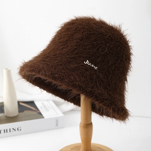 Vue détaillée du chapeau bob en peluche marron avec plaque métallique sur support bois
