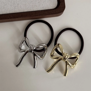 Detail of gold and silver metal bow hair ties with high-elasticity rubber bands