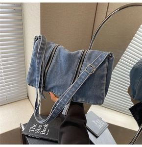 Detaillierte Nahaufnahme der blauen Denim-Tasche mit Metallreißverschlüssen und Trageriemen