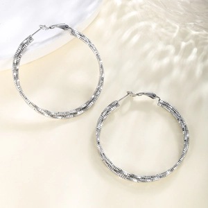 Close-up of silver chain textured hoop earrings with a dual intertwined ring design