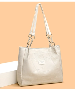 Detail of off-white tote bag with geometric stitching texture and chain strap accents
