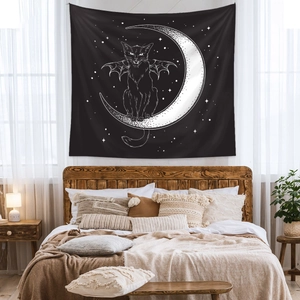 Detail of bat-winged cat on crescent moon tapestry hanging above a wooden headboard