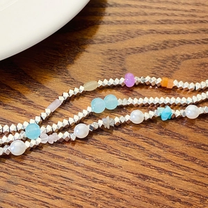 Close-up of faceted silver beads and colorful pearls on a multilayered necklace