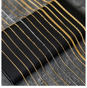 Detailed close-up of various gold and silver titanium steel necklace chains on a black display