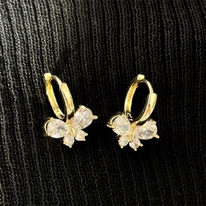 Close-up of gold butterfly hoop earrings with sparkling white cubic zirconia stones