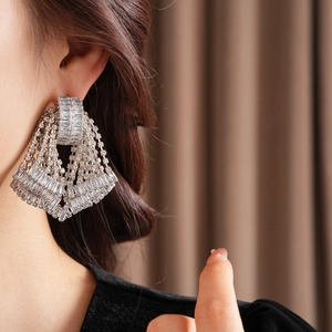 Close-up of sparkling bow-knot tassel earrings with rhinestones worn by a model
